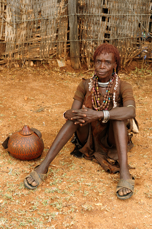 DIMEKA, OMO VALLEY, ETHIOPIA - JULY 27: Portrait of the woman from Hamer people resting by the fence in transit to the local marketplace in Dimeka, Omo valley in July 27, 2013のeditorial素材