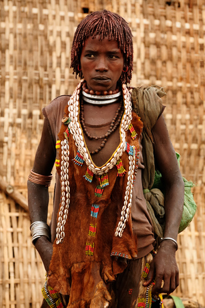 DIMEKA, OMO VALLEY, ETHIOPIA - JULY 27: Portrait of the woman from Hamer people resting by the fence in transit to the local marketplace in Dimeka, Omo valley in July 27, 2013のeditorial素材