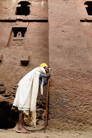 Ethiopian pilgrim is praying by the wall of church carve in solid rock in Lalibela, Ethiopiaのeditorial素材