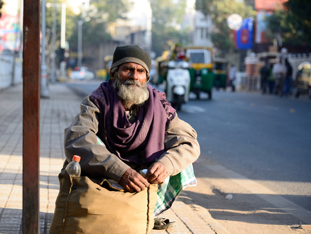 AHMADABAD, GUJARAT, INDIA - JANUARY 30: The poor Indian peasant is waiting for the bus squatting by the sack with the rice in the Ahmedabad city in the Gujarat state in India, Ahmadabad in January 28, 2015のeditorial素材
