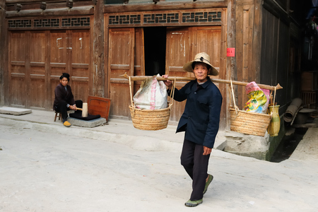ZHAOXING, CHINA - 12 NOVEMBER 2010: Residents of the Zhaoxing is a pretty Dong minority town carrying things on the stick for the saleのeditorial素材