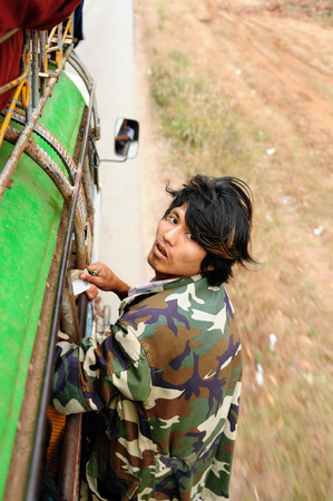 HPA AN, MYANMAR - 10 JANUARY 2011: Portrait of the man taking fares on the local bus in Burma which is trying to get to the roof of the vehicleのeditorial素材