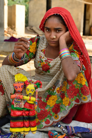 BHUJ, RAN OF KUCH, INDIA - 14 JANUARY 2015: The tribal woman in the traditional dress selling souvenirs for tourists in the ethnic village on the desert in of Ran of Kuch in the Gujarat state in India, Ran of Kuchのeditorial素材