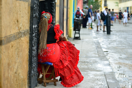 HAVANA, CUBA - 10 DECEMBER 2016: The resident of Havana in the traditional dress is staying in front of the colonial house in the old city centre, amongst crowds of touristsのeditorial素材
