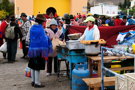 ECUADOR, PUJILI - 11 AUGUST 2012; Indigenous Ecuadorian woman in national clothes selling fresh food on a market in the Pujili villageのeditorial素材