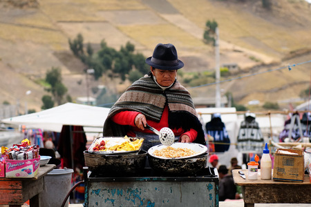 ECUADOR, PUJILI - 11 AUGUST 2012; Ecuadorian ethnic woman in national clothes selling food other food items on a market in the Pujili villageのeditorial素材