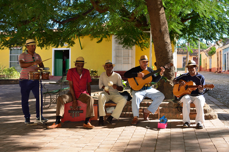 TRINIDAD, CUBA - 08 NOVEMBER 2016:  Latino American men of musicians play on maracases, guitar and small drums and sing songs on the square in Trinidadのeditorial素材