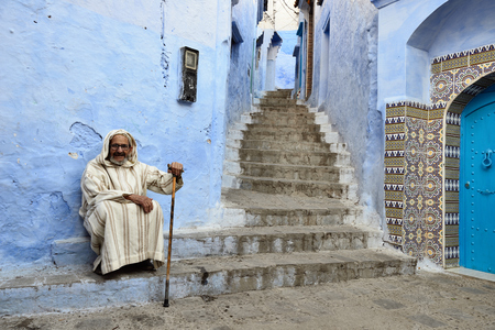 CHEFCHAOUEN, MOROCCO - 27 NOVEMBER 2015:  Older man sitting on the doorstep of the house in the blue city in Moroccoのeditorial素材