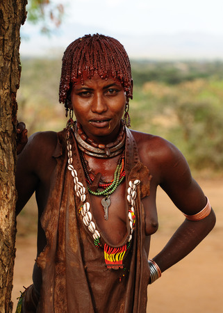 TURMI, OMO VALLEY, ETHIOPIA - 29 JULY 2013: Portrait of the woman from Hamer people resting under the tree in transit to the local marketplace in Omo vallezのeditorial素材