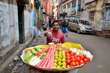 CALCUTTA, WEST BENGAL INDIA - 21 DECEMBER 2018: Seller of vegetables in of wicker basket on crowded streets of Calcutta in the West Bengalのeditorial素材