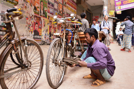 DHAKA, BENGAL BANGLADESH - 28 JANUARY 2019: Rickshaw driver is cleaning wheels in his rickshaw on crowded streets of Dhaka in the Bangladeshのeditorial素材
