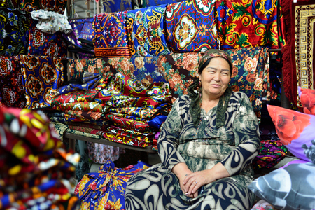 MARGILAN, FERGANA VALLEY, UZBEKISTAN - 02 JUNE 2019: Uzbek woman selling clothes in the Margilan market in the Fergana valleyのeditorial素材