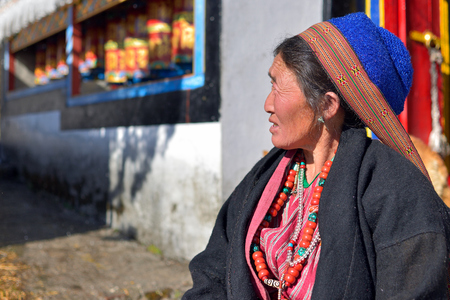 Tawang, Arunachal Pradesh, India - 04 JANUARY 2019: Portrait of the india, tribal woman dressed in the yak hair hat, in the background there are monastery and prayer mills.のeditorial素材