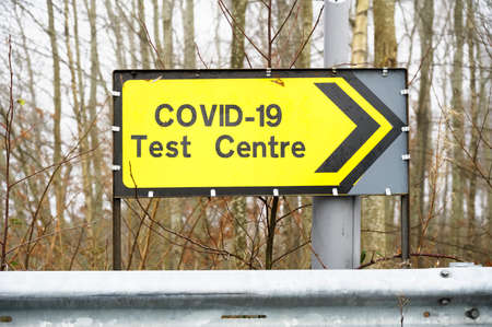 Covid-19 test centre sign at road with traffic cones