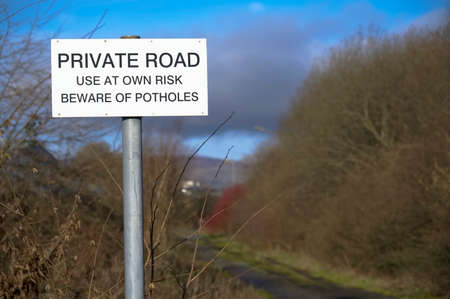 Beware of potholes private road sign in countrysideの写真素材
