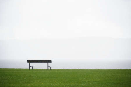 Lonely empty bench in open tranquil landscape by the sea for mindfulness and meditationの写真素材