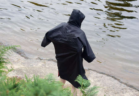 Man in dry changing robe after wild swim outdoorsの写真素材
