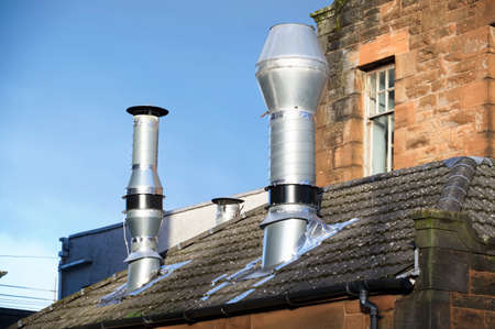 Flue chimney fixed to building exterior wall stainless steel from exhaust boiler plant roomの写真素材