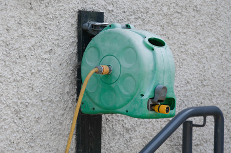 Yellow rubber hose and wall mounted holder outdoorsの写真素材