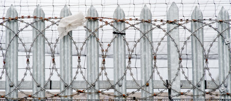 Razor wire warning sign on security fence at construction siteの写真素材