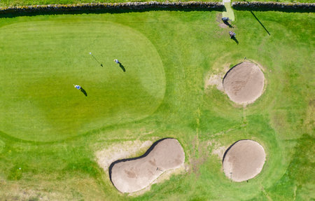 Golf course green aerial view and two playersの写真素材