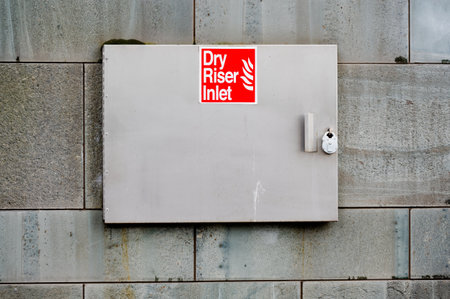 Dry riser red inlet box and sign at wall