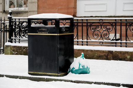 Black litter bin for rubbish collection during the winterの写真素材