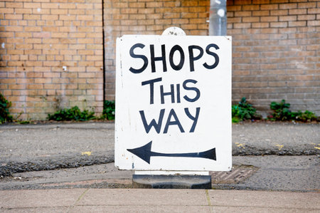 Shops this way direction arrow sign on street