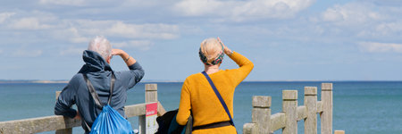 Senior elderly female couple looking out to sea
