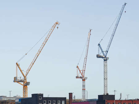 Tower cranes high in sky at construction siteの写真素材