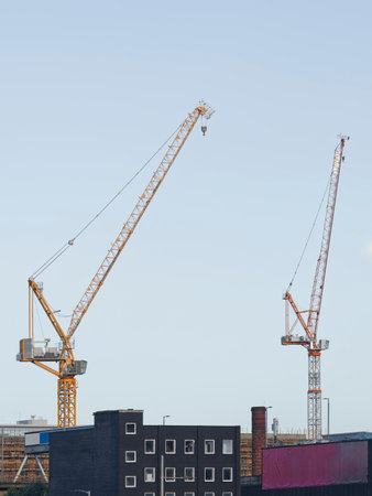 Tower cranes high in sky at construction siteの写真素材