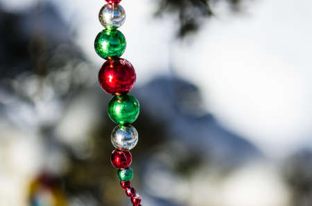 Red, Green and Silver Christmas Ornament Beads Decorating a Snowy Outdoor Treeの写真素材