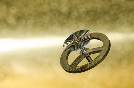 Watch Repair: Vintage Pocket Watch Hairspring Resting on a Golden Surfaceの写真素材