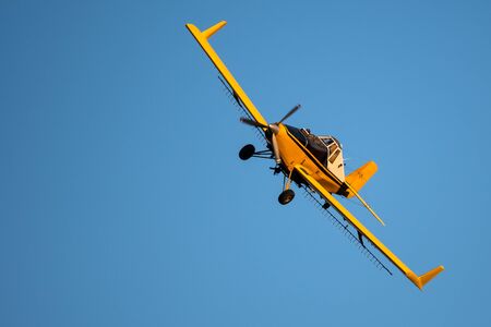 Yellow Crop Dusting Plane Flying in a Blue Skyの写真素材