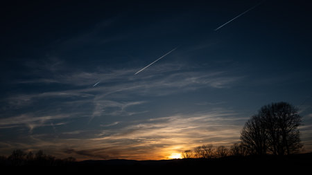 Three Contrails Streaking Across the Sky as the Sun Setsの写真素材