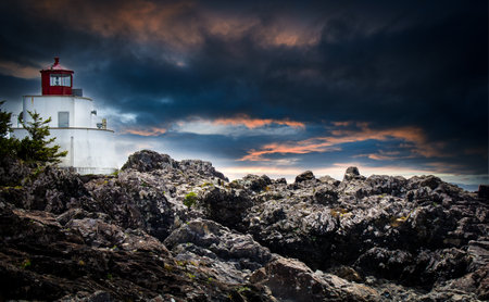 A traditional lighthouse on the rocky West Coast of Vancouver Island near Pacific Rim National Park under a dramatic sky.の写真素材
