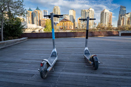 Calgary Alberta Canada, May 16 2022: Two electric scooters parked on a waterfront pathway...