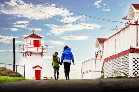 Fort Amherst Newfoundland Canada, September 17 2022: Brother and sister walk towards a historic lighthouse along the battery holding hands at a popular tourist attraction.のeditorial素材
