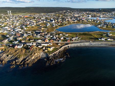 Aerial East Coast Newfoundland town with colourful beach homes on rocky shores and the historic Old Bay Pond with distant water towers.のeditorial素材