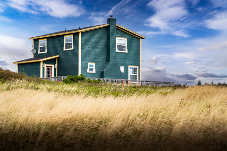 Skerwink Newfoundland Canada, September 24 2022: A Newfoundland home with painted wooden siding overlooking a grassy field and Atlantic Ocean along the Skerwink Hiking Trail.のeditorial素材