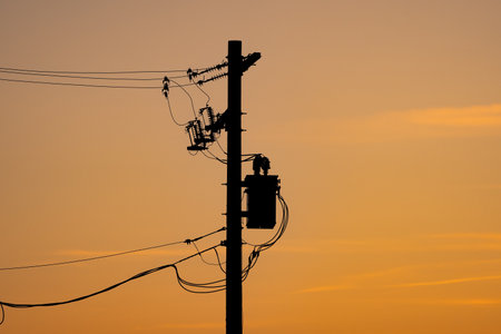 Power pole silhouette with resistors and transformers on a power grid under a sunset sky in Alberta Canada.の写真素材