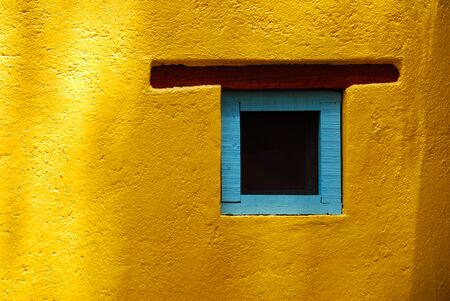Rustic window in San Miguel de Allende, Spanish colonial town in Mexico. Blue turquoise window on a yellow wall.の写真素材