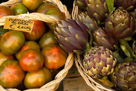 Display of artichokes and tomatoes for sale in a market.の写真素材