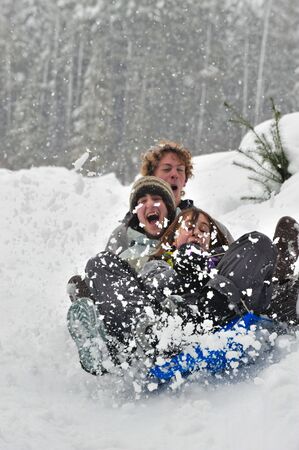Teenagers sledding in the snow on a saucer. Winter fun.の写真素材