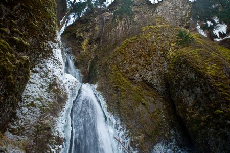 Winter waterfall surrounded with snowの写真素材