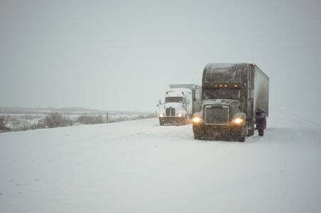 Truckers putting on chains in a fierce winter stormの写真素材
