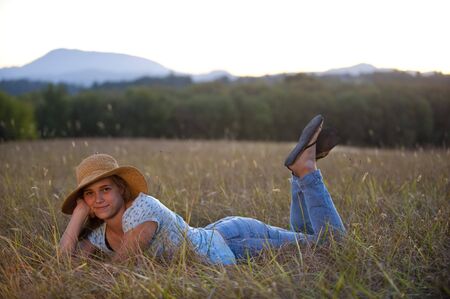 Pretty teen girl, straw hat, lying in field.の写真素材