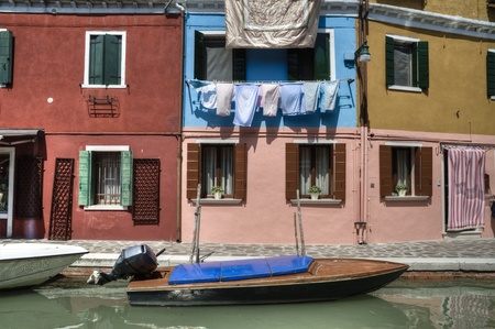 Laundry hanging on a line above colorful houses in Burano Italyの写真素材