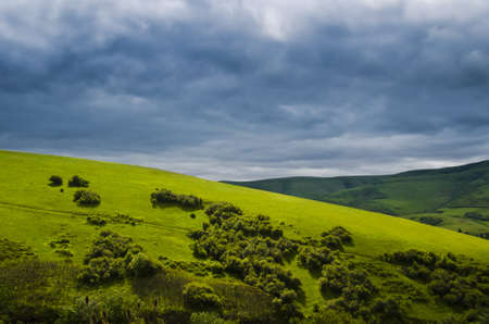 Hilly landscape of grass with dramatic clouds