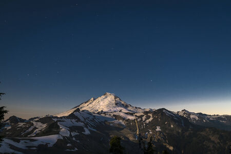 Snowcapped Mount Baker, under sky full of stars, lit by the full moon